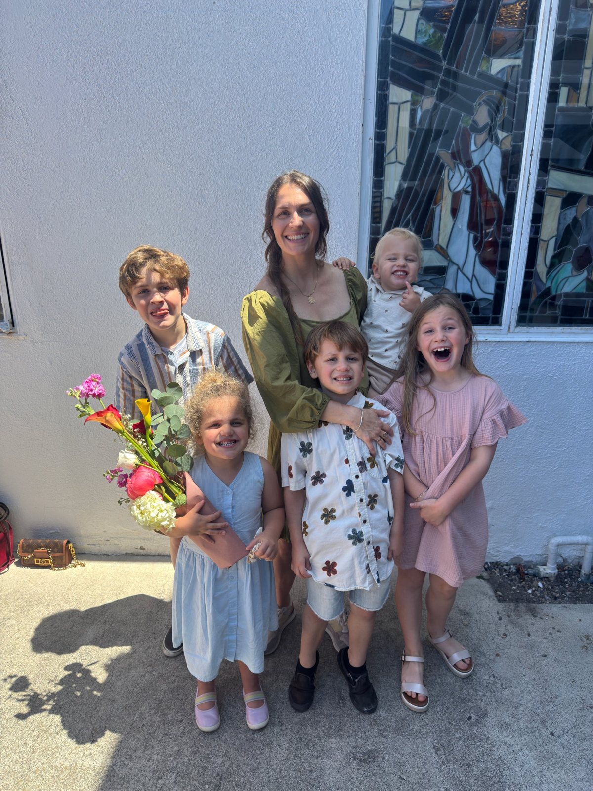Haley and the five children outside Saint Michael’s, in front of a stained-glass window, one of them holding a bouquet.