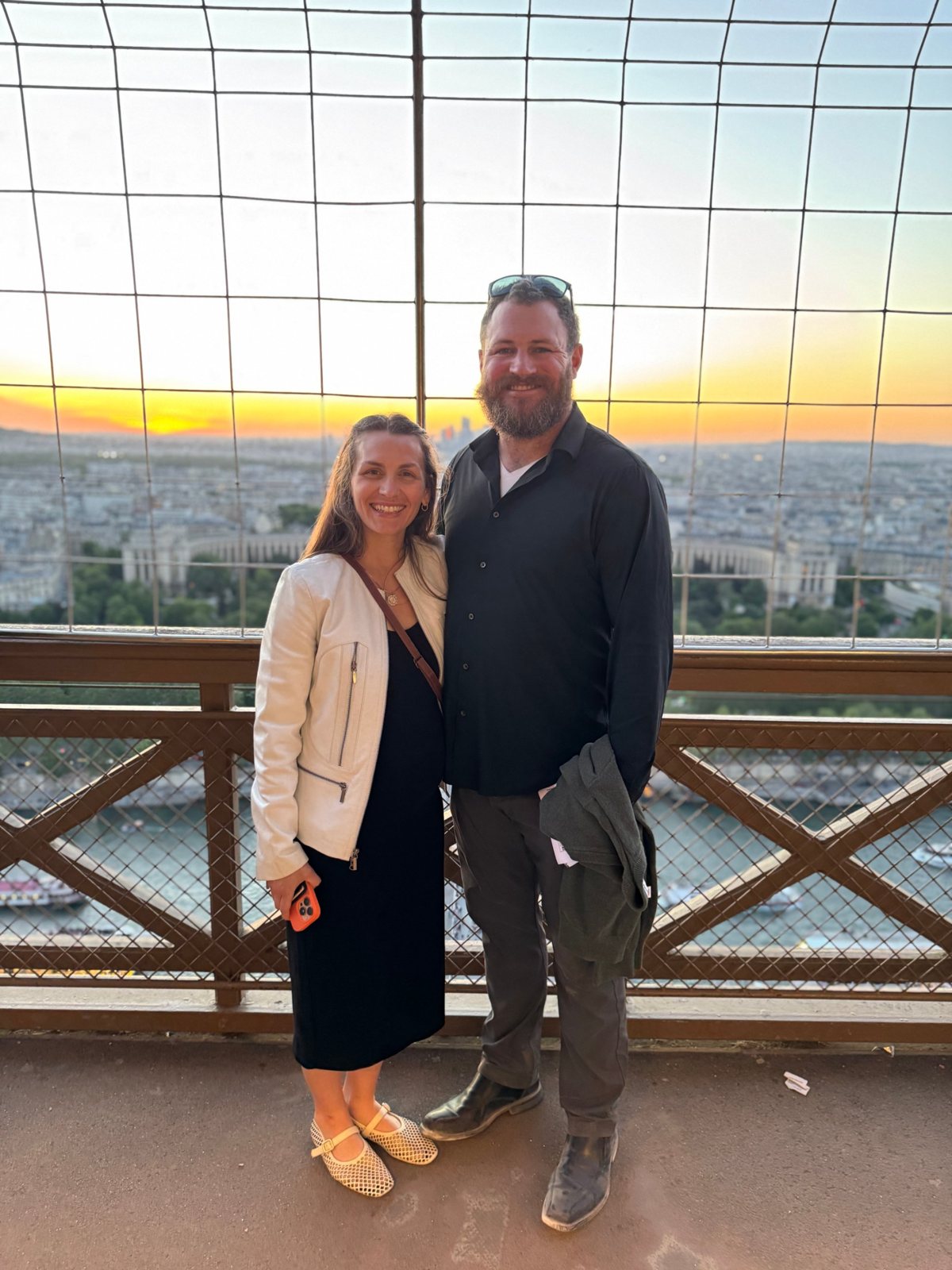Jesse and Haley at sunset on the Eiffel Tower, the city behind them.